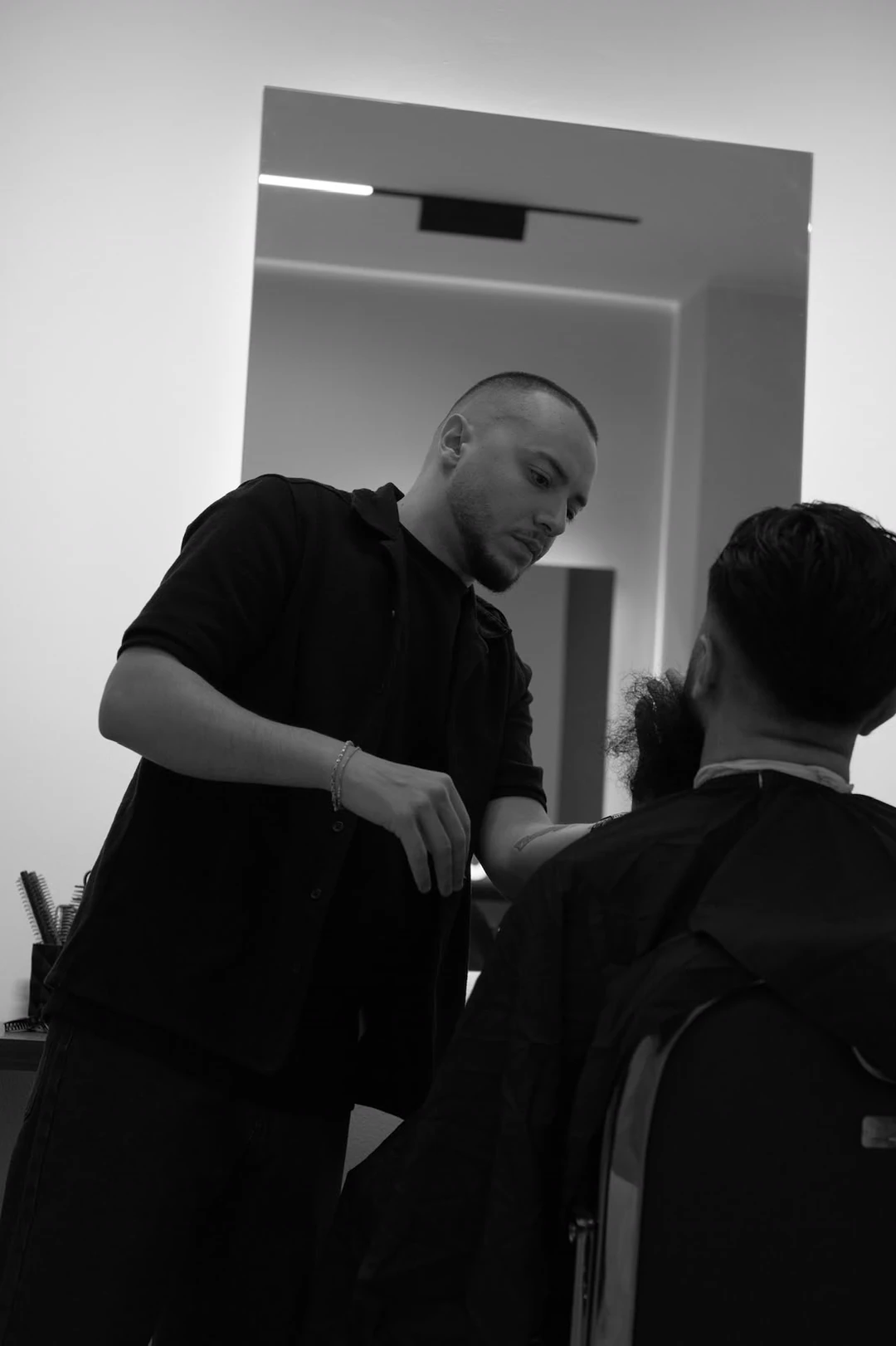 A barber working on a client at the mirror.