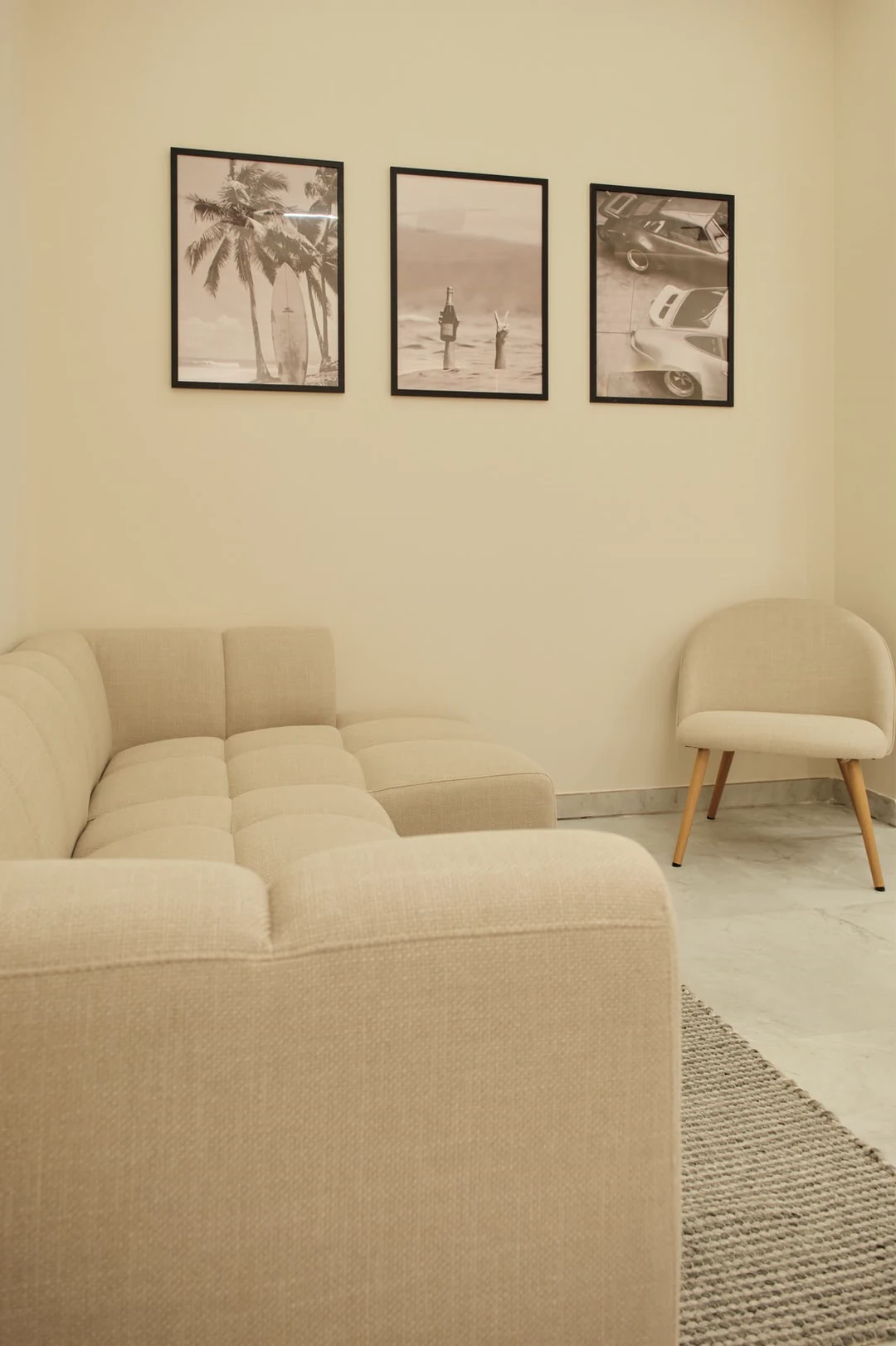 The waiting area: a cream bouclé sofa and armchair under three framed prints.