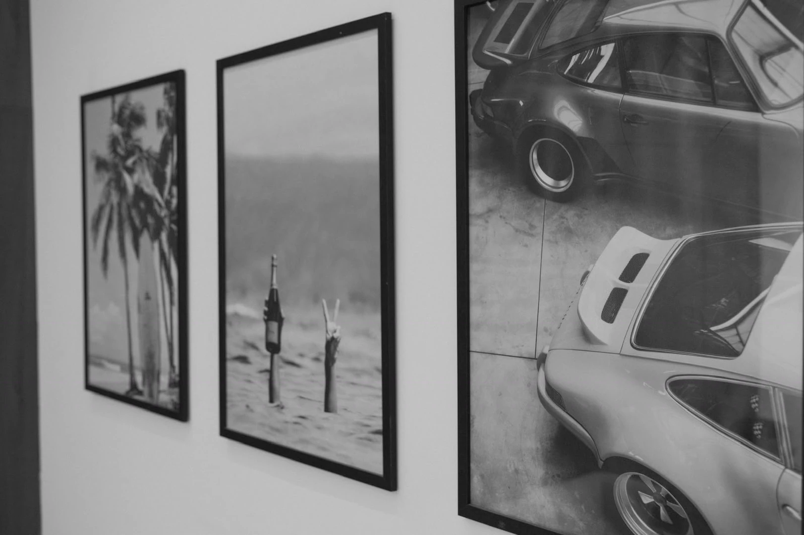 Three framed black and white prints on the studio wall: palms, a beach, and a vintage car.