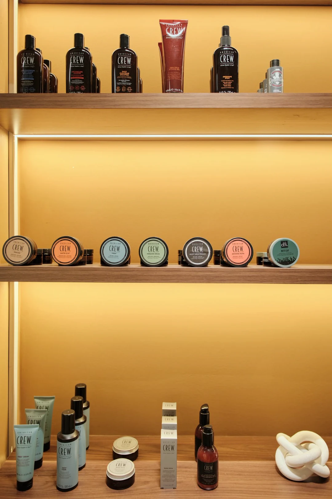 Grooming products on walnut shelves, each shelf lit warm from beneath.